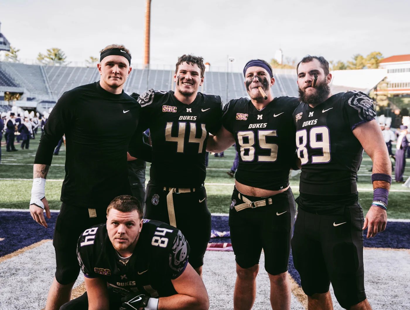 JMU teammates and tight ends together on the field in black football uniforms.