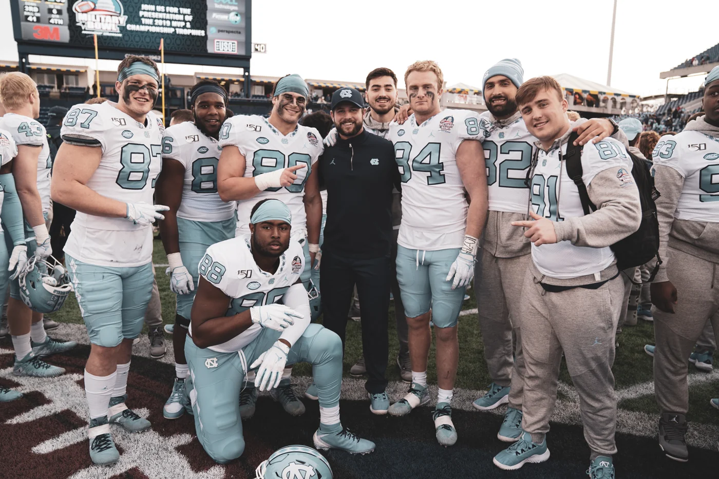 UNC teammates and tight ends together on the field in Carolina blue and white uniforms.